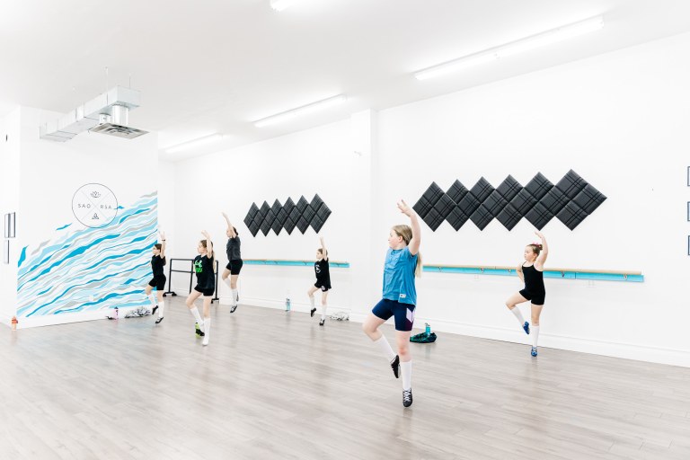 A children's dance class with 6 participants does a dance in a large white studio