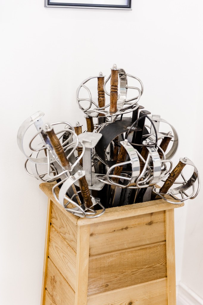 Silver sword hilts stick out of a wooden sword box