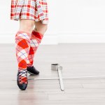 A highland dancer wearing red points their foot over silver swords