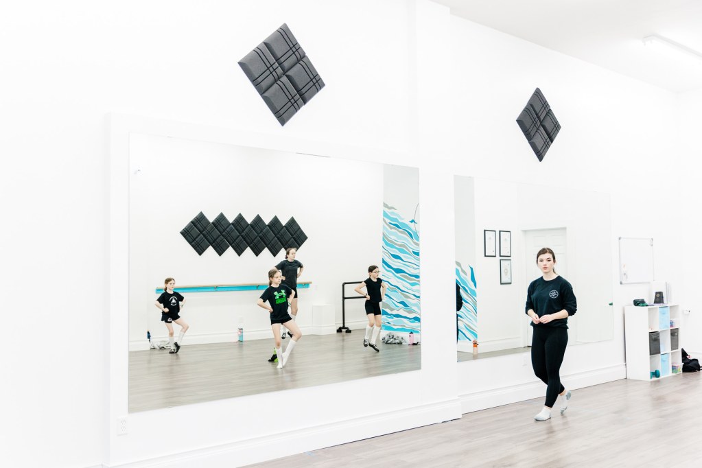 A woman instructs a children's dance class with 4 students