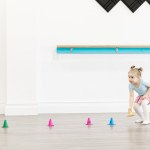 A toddler plays with coloured cones in a white room