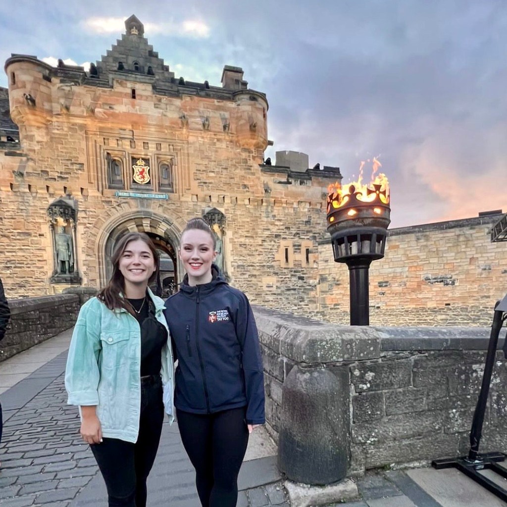 Two women smile in front of a castle