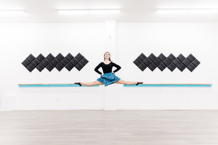 A dancer in a blue kilt does a jump