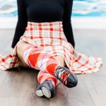A dancer's legs in a read kilt with black dance shoes and red socks