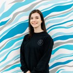 A woman wearing a black shirt in front of a blue and white wall