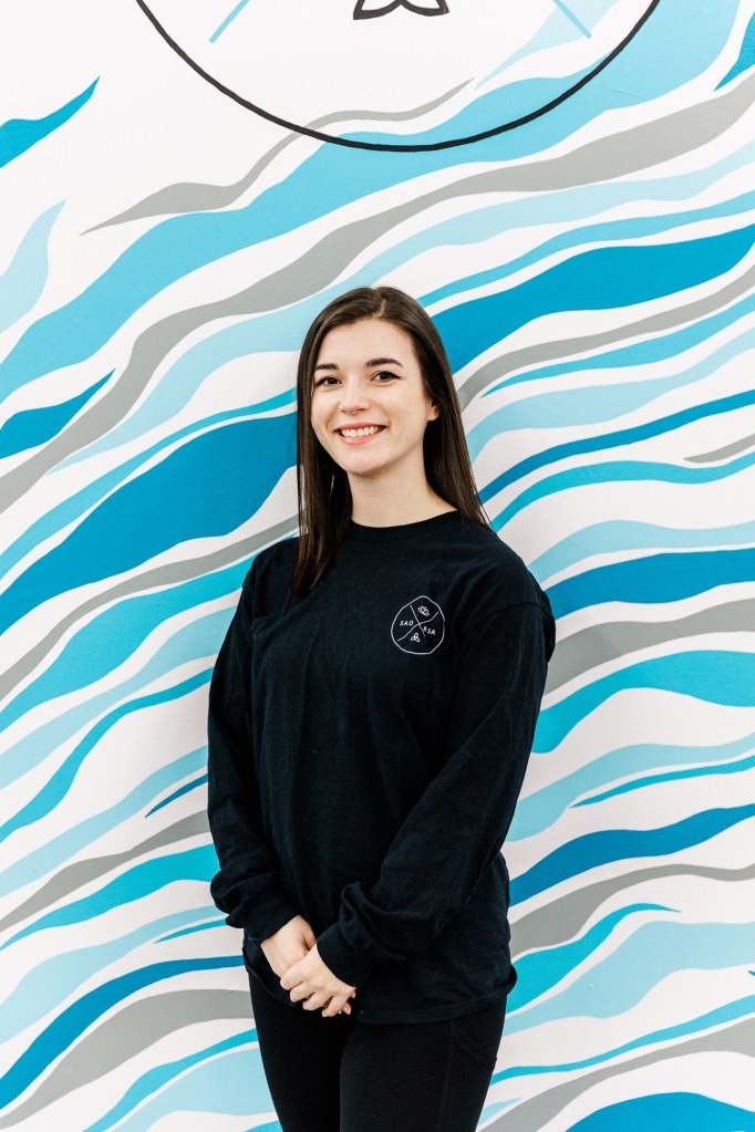 A woman wearing a black shirt in front of a blue and white wall