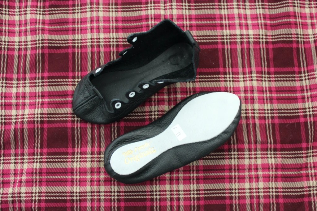 Black dance shoes on a red plaid background