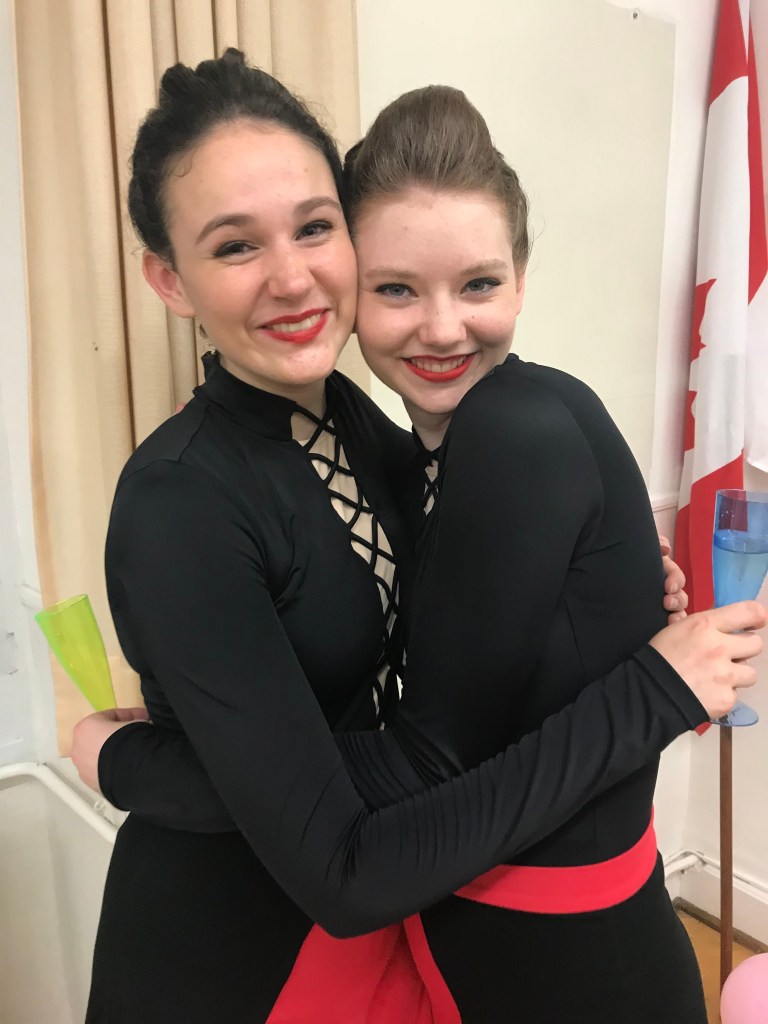 Two women hug wearing black