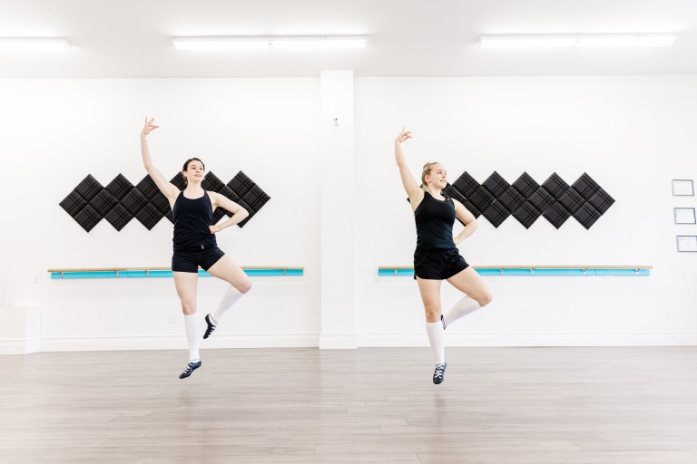 Two dancers pose in a white room
