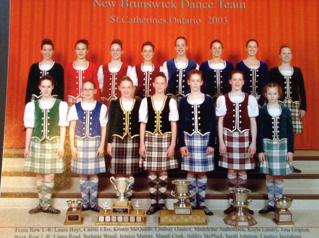 A group of dancers posing in multi colour kilts