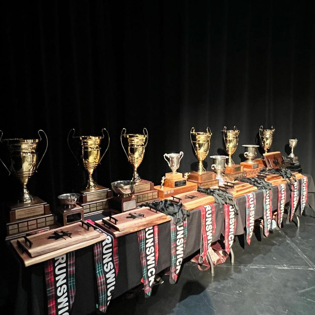 A table covered in trophies and sashes that read "New Brunswick"