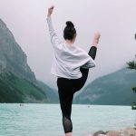 A dancer poses in front of mountains and a lake