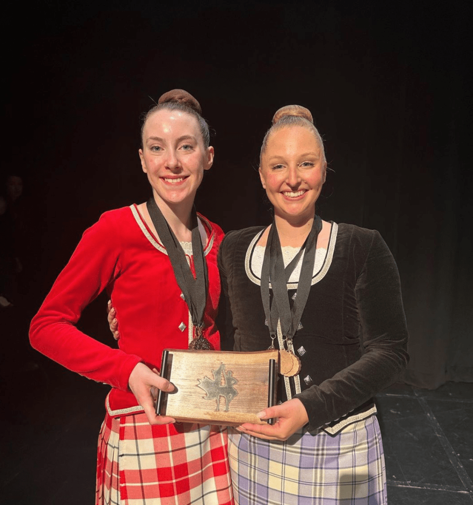 Two dancers smile holding a plaque