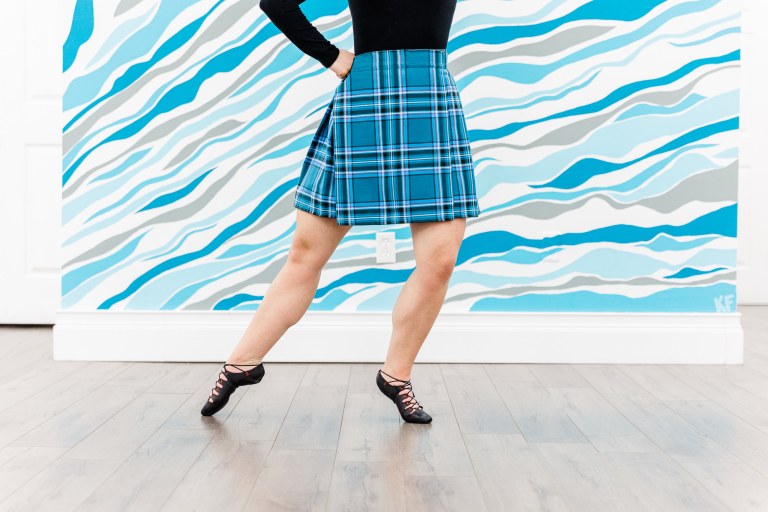 A dancer posed in front of a blue and white wall