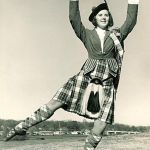 A black and white image of a woman in a kilt posing