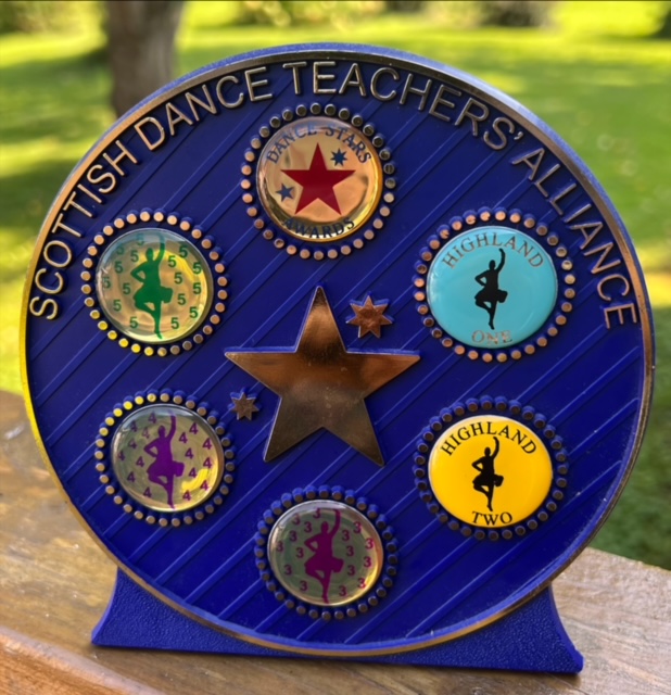 a circular plaque that reads "Scottish dance teachers alliance"