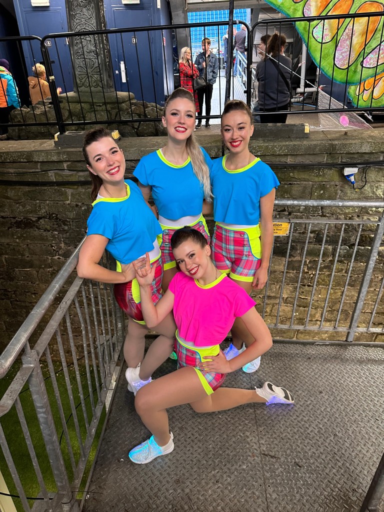 4 women in neon clothing smile