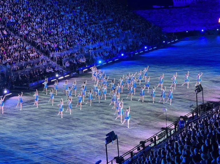 An area with a large crowd, and performers in a star formation on a large stage