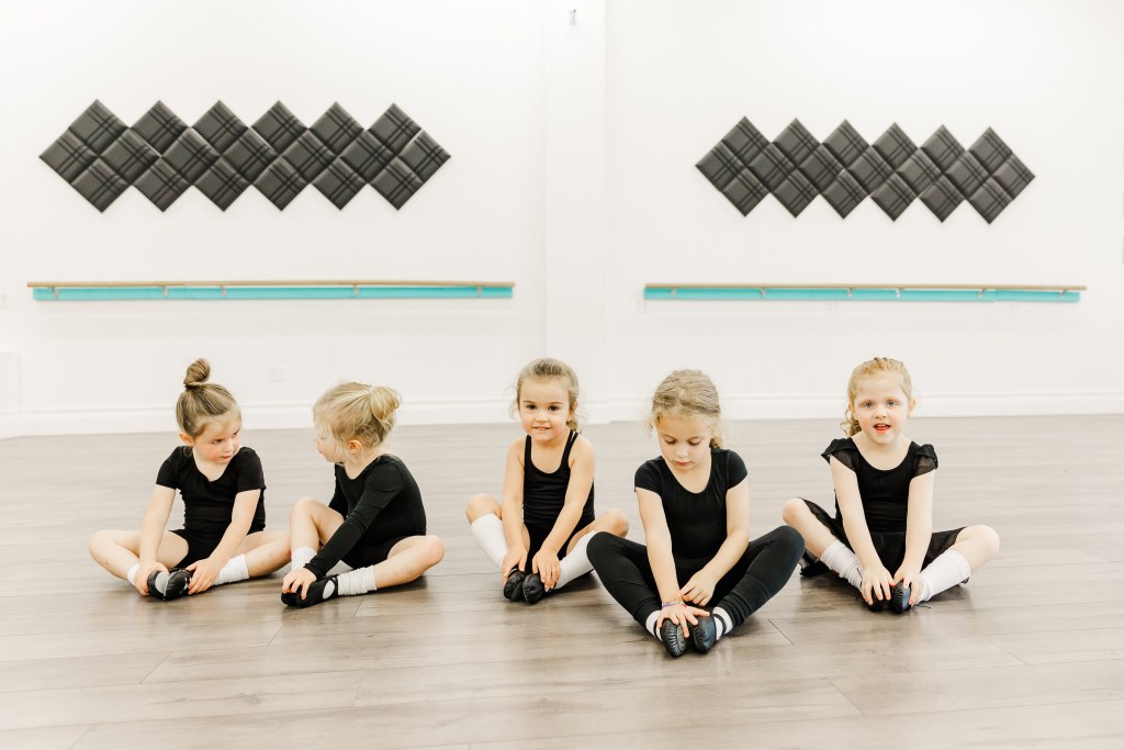 5 young dancers stretch in a white room