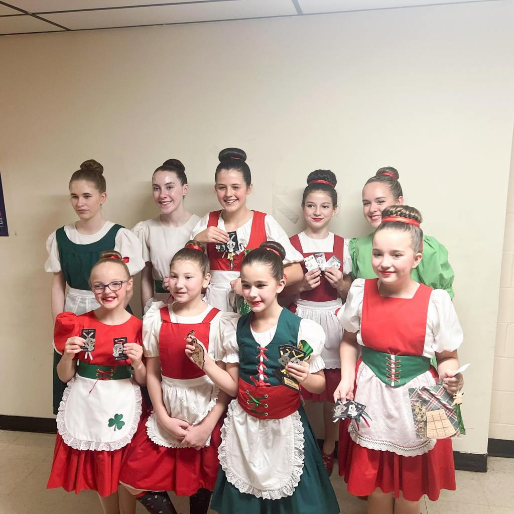 9 dancers in red and green outfits smile