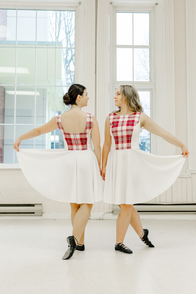 Two dancers pose in a white room