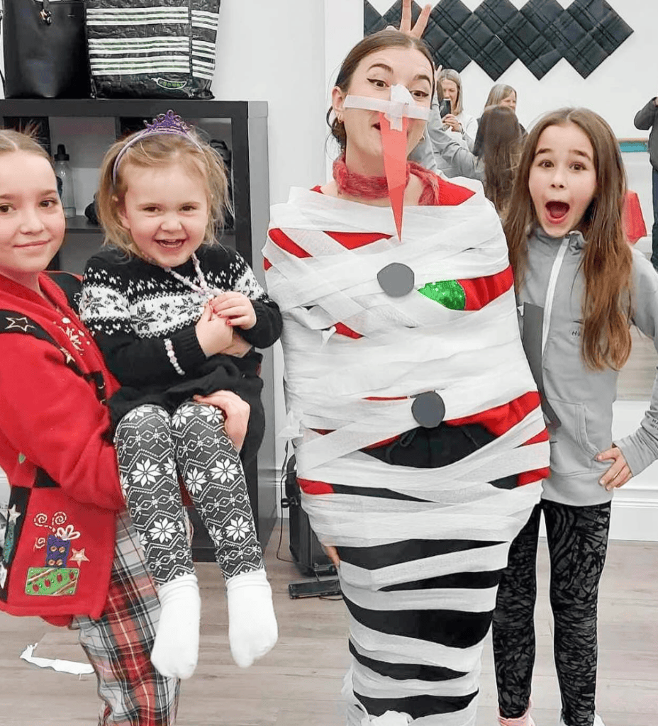 4 people smile in Christmas sweaters