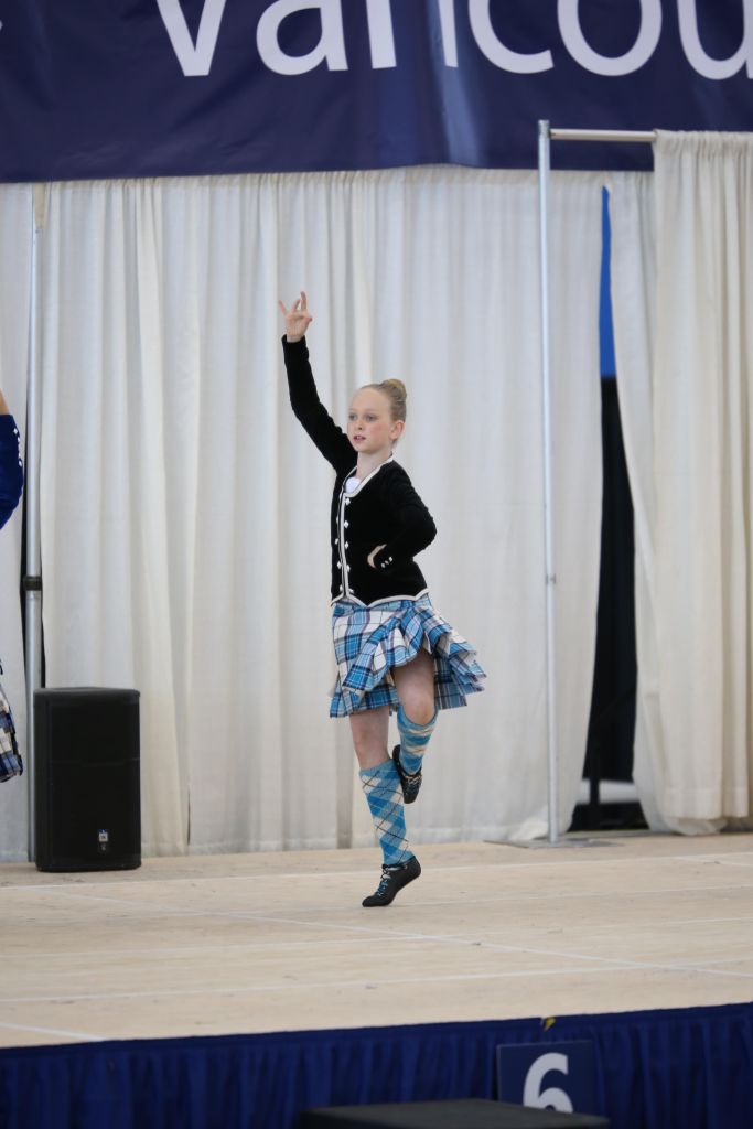 A dancer on a stage in a blue kilt and black top