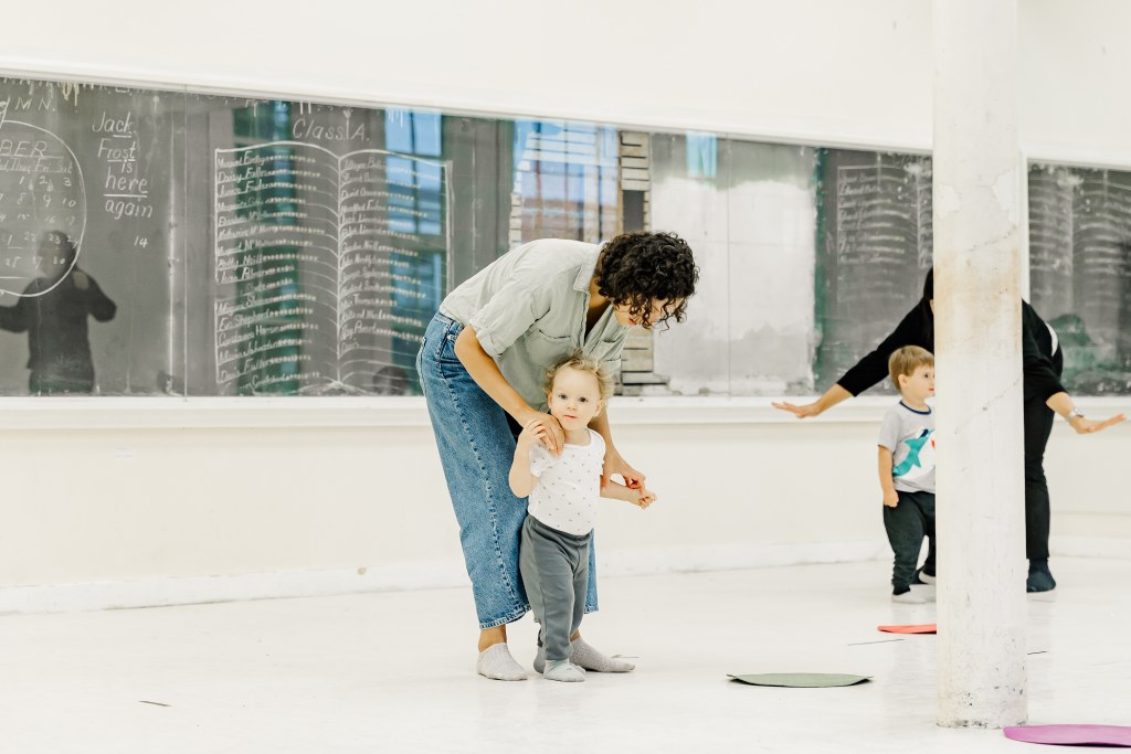 A mother and child dance in a white room