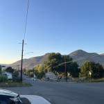 A city street with brown mountains in the background and a blue sky
