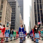 Rows of dancers in kilts smile and wave, surrounded by sky scrapers. Saorsa Studio Highland Dance Fredericton.