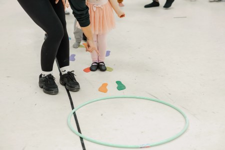 A person wearing black helps guide a child wearing pink to jump around colourful dance class obstacles. Saorsa Studio offers Highland Dance classes for ages 1 to adult in Fredericton, New Brunswick.