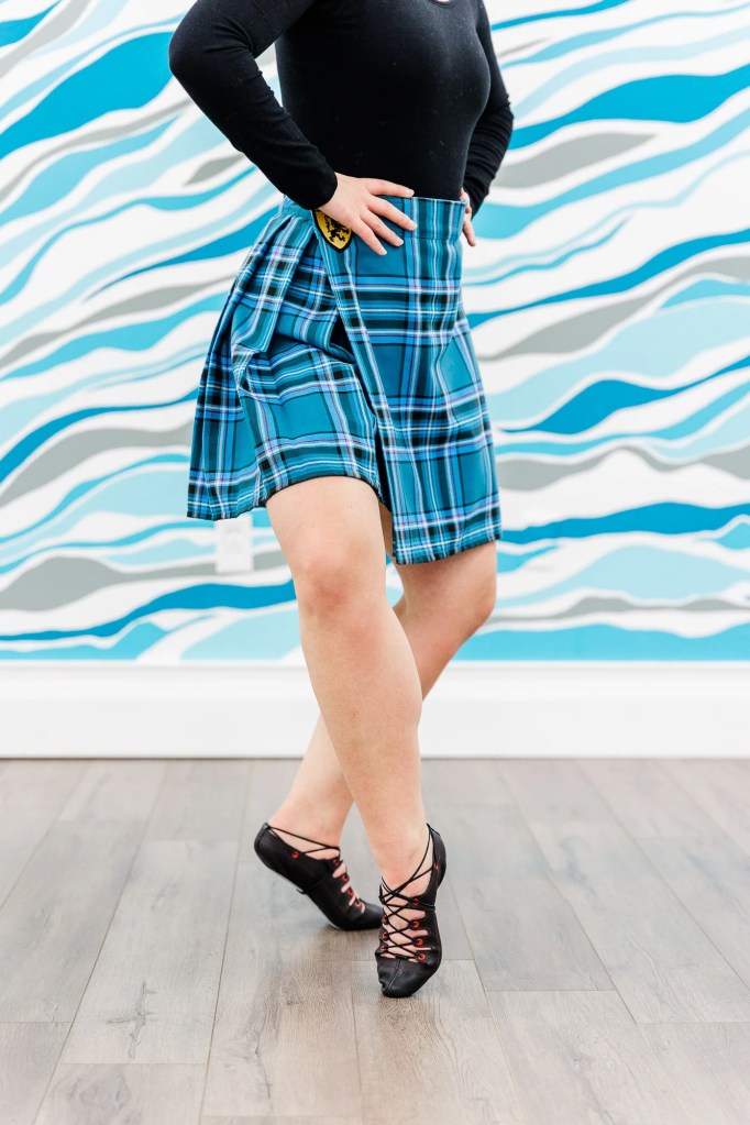 A highland dancer in a blue kilt demonstrates a Scottish dance position. Saorsa Studio offers Highland Dance classes for ages 1 to adult in Fredericton, New Brunswick.